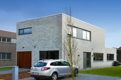 Moderne kubuswoning in lichtgrijze baksteen en met houten poort