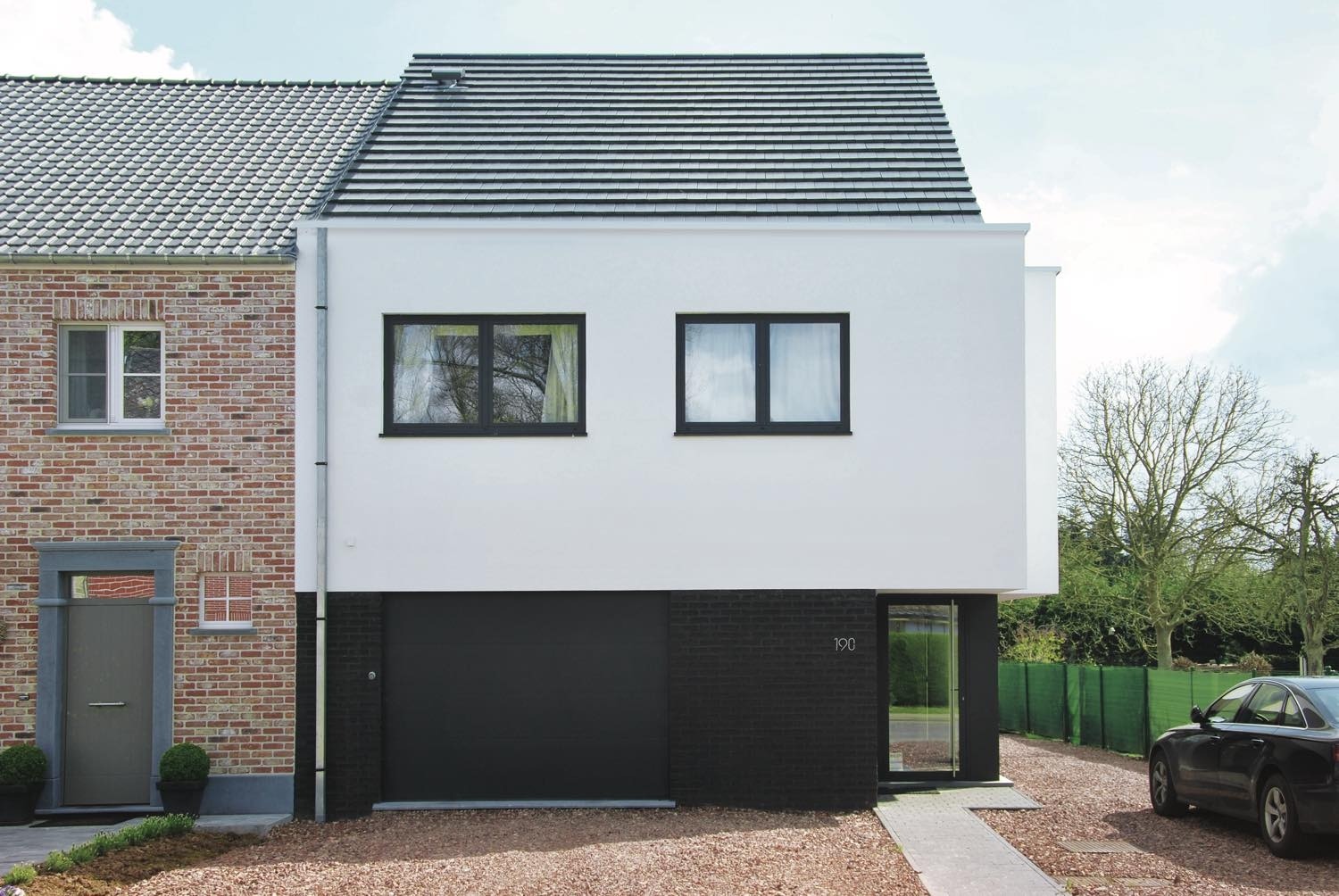 Halfopen bebouwing: moderne woning met witte crepi en zwarte baksteen