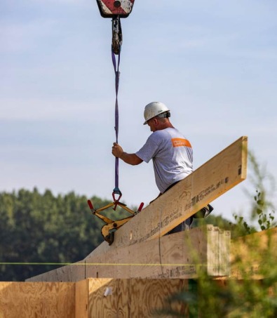 Plaatsing houtskeletbalk met hijskraan op werf.