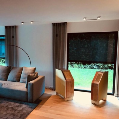 Salon avec vue sur jardin et protection solaire intérieure noire.