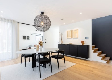 Moderne eetkamer met zwarte accenten en houten trap in een energiezuinige houtskeletbouwwoning.