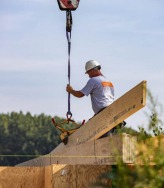 Plaatsing houtskeletbalk met hijskraan op werf.