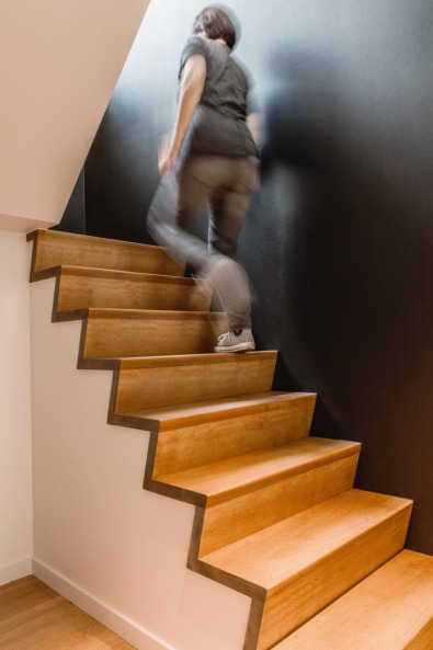 Escalier en bois design contre mur noir dans une maison témoin Dewaele.