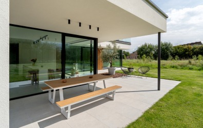 Terrasse d’une maison moderne à ossature bois avec grandes baies vitrées.