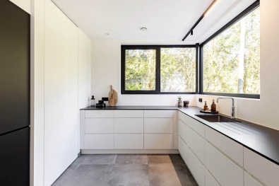 Moderne keuken met zwart werkblad en grote ramen in kijkwoning.