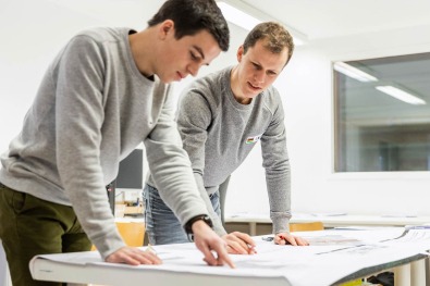 Twee collega’s bespreken bouwplannen aan tafel.