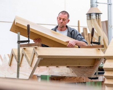 Schrijnwerker van Dewaele aan het werk aan een houten trapconstructie.