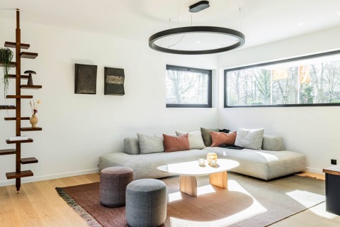Zithoek met moderne hoekzetel en grote ramen in een kijkwoning.
