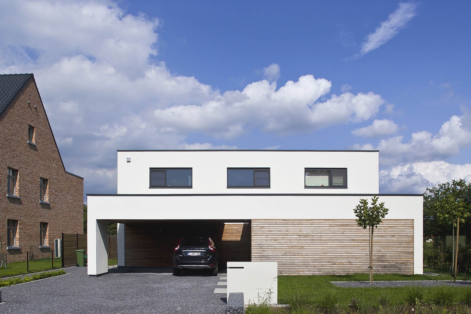 Moderne woning met carport en afgewerkt met witte crepi en houten gevelbekleding